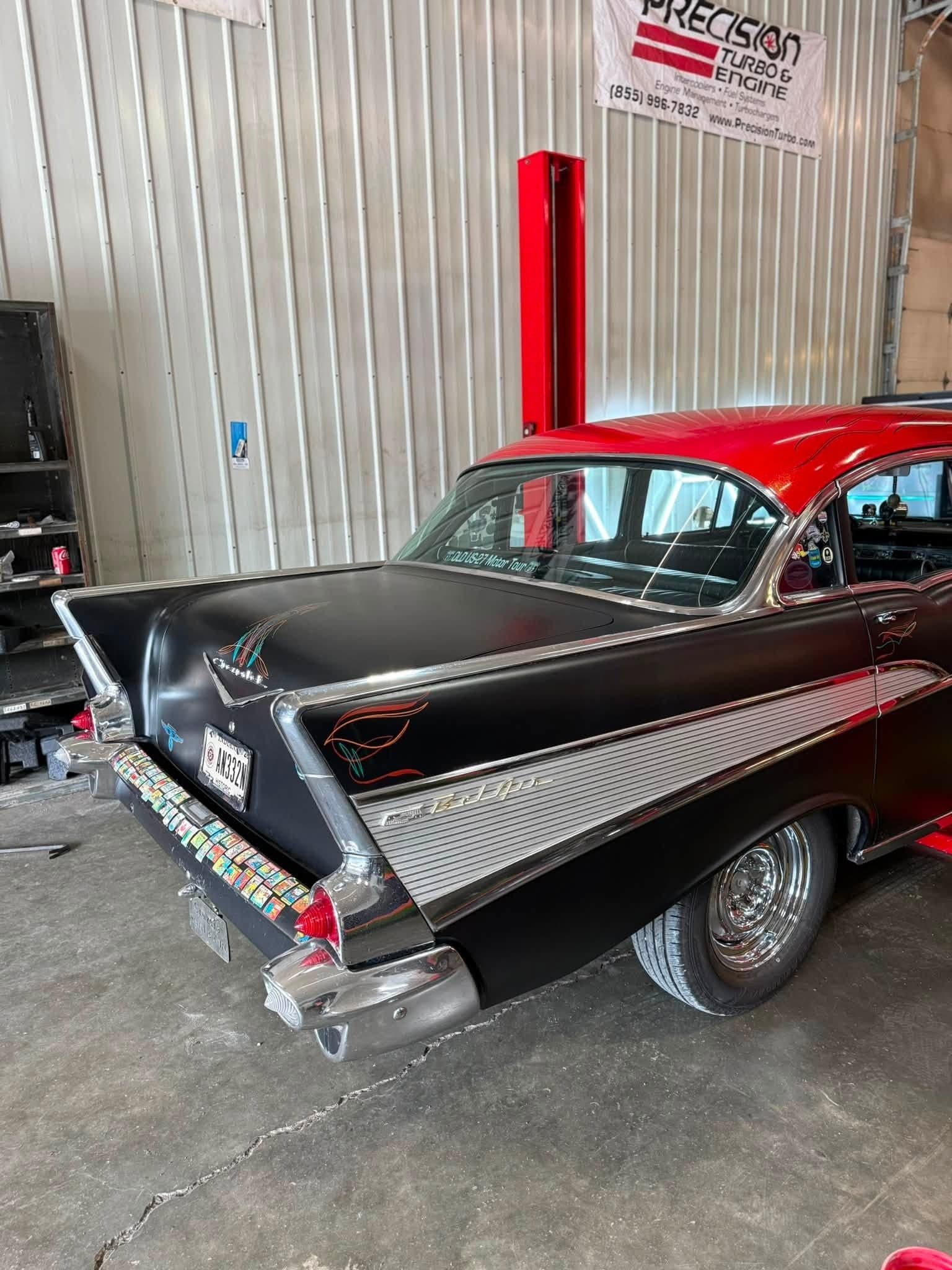 Rear three-quarter view of a black and red 1957 Chevy Bel Air with chrome trim and pinstriping