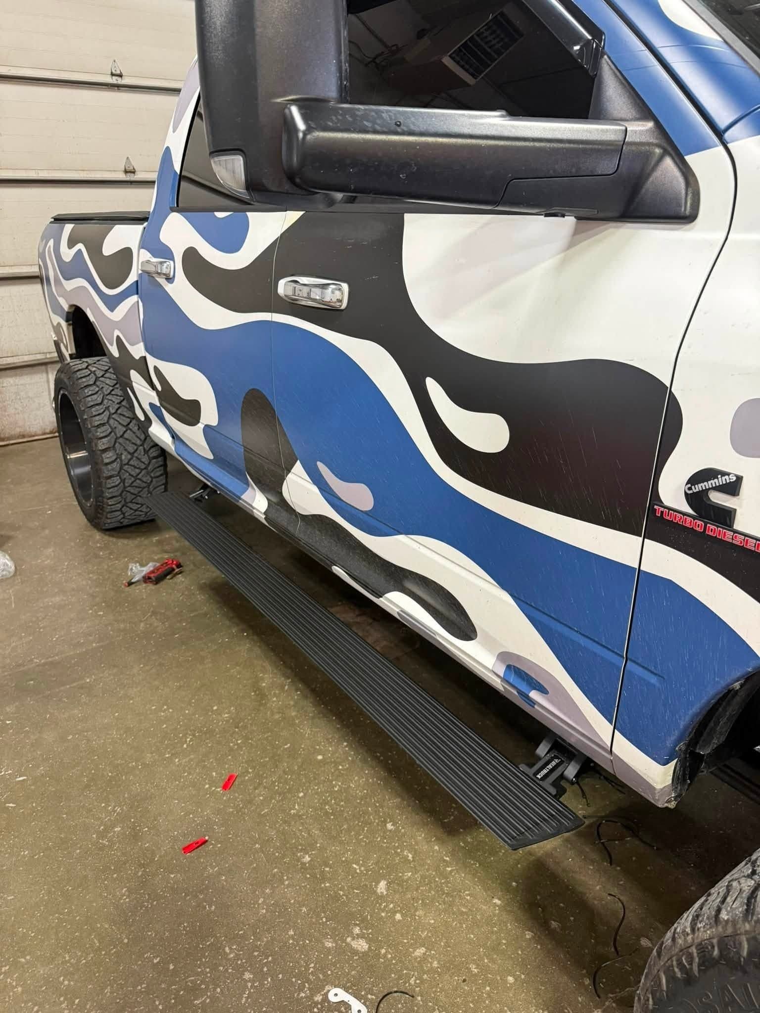 Power running board install on a camo-wrapped Ram Cummins turbo diesel truck