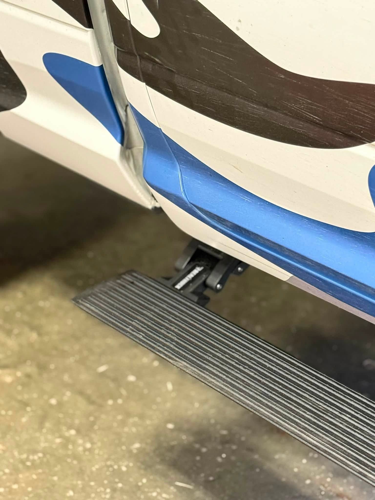 Close-up of an automatic deploying running board under a wrapped diesel truck